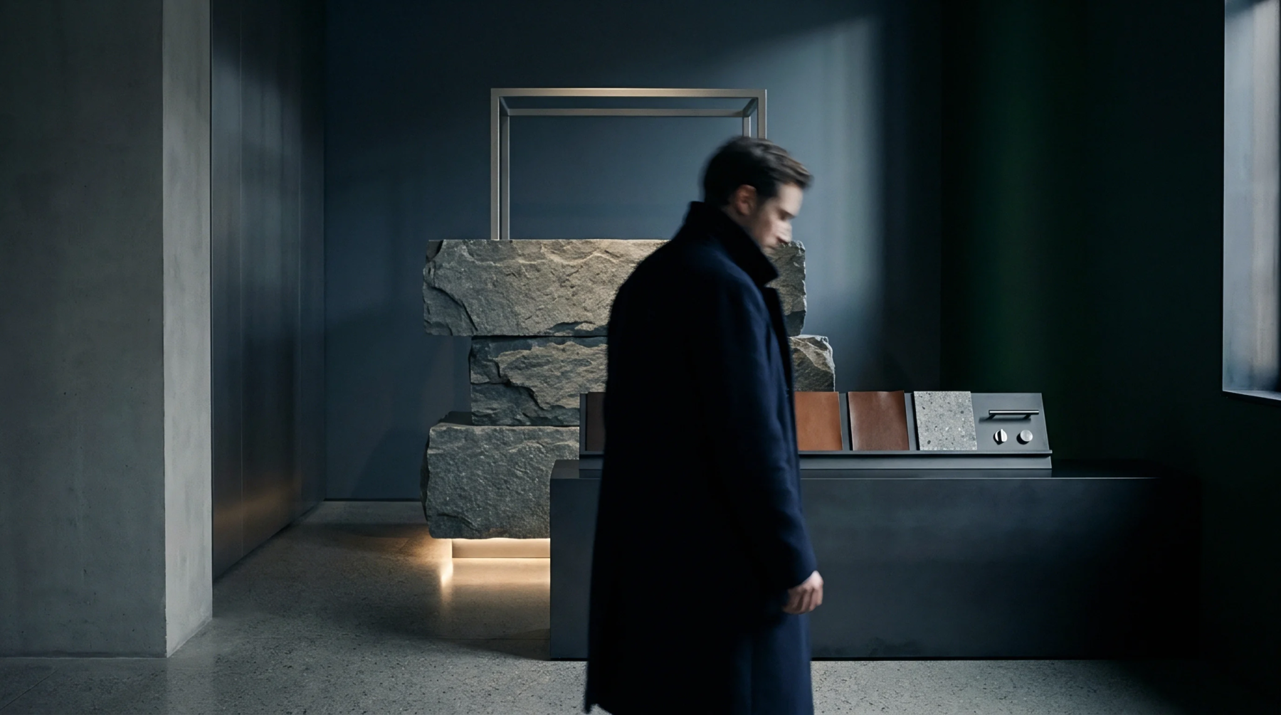A man walks past a curated display of material swatches including leather and stone finishes within a modern showroom setting.