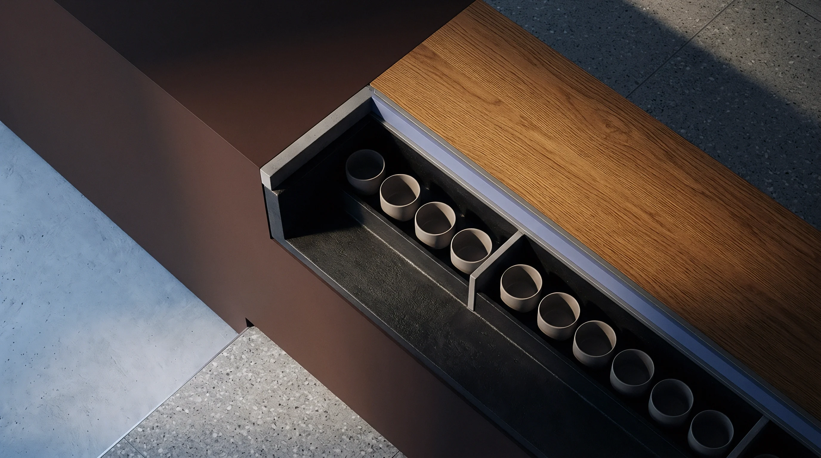 A recessed tray within a wood and dark composite retail counter holds rows of identical ceramic vessels on a terrazzo floor.